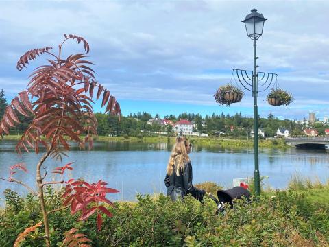 Kona á göngu með barnavagn í Hljómskálagarðinum.