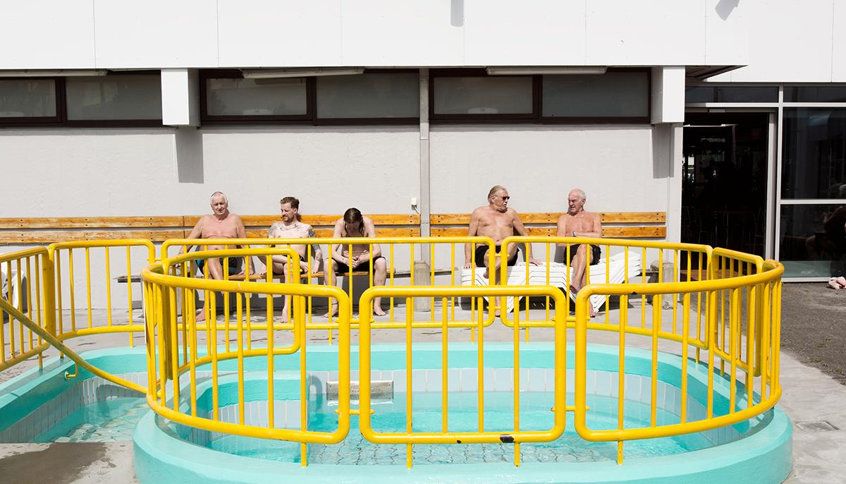 Swimming pool visitors sunbathing on benches at Breiðholtslaug
