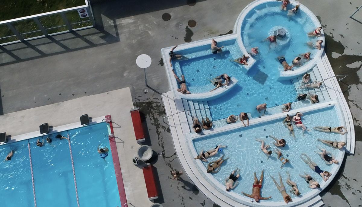Loftmynd af fólki í sundlaug og pottum Vesturbæjarlaugar