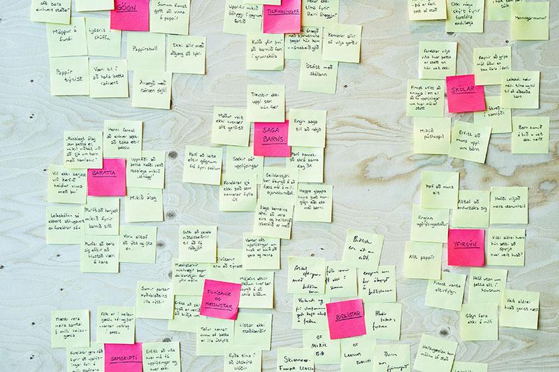 Mynd af post-it miðum á vegg í þemagreiningu.