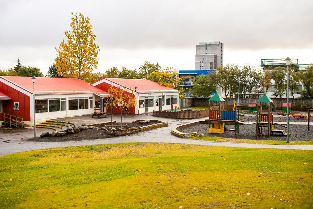 Leikskólinn Bjartahlíð séð frá grasbala á útisvæði