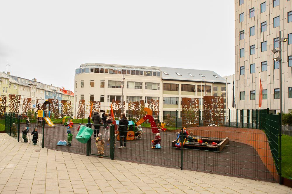 Children and adults with playground equipment on the grounds of the nursery school at Bríetartún.