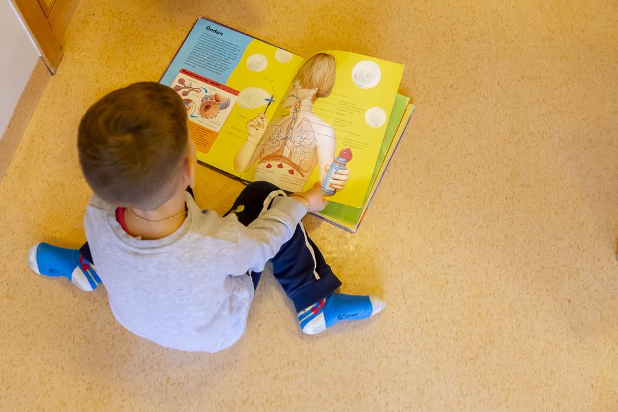A child reading a book, seen from above.