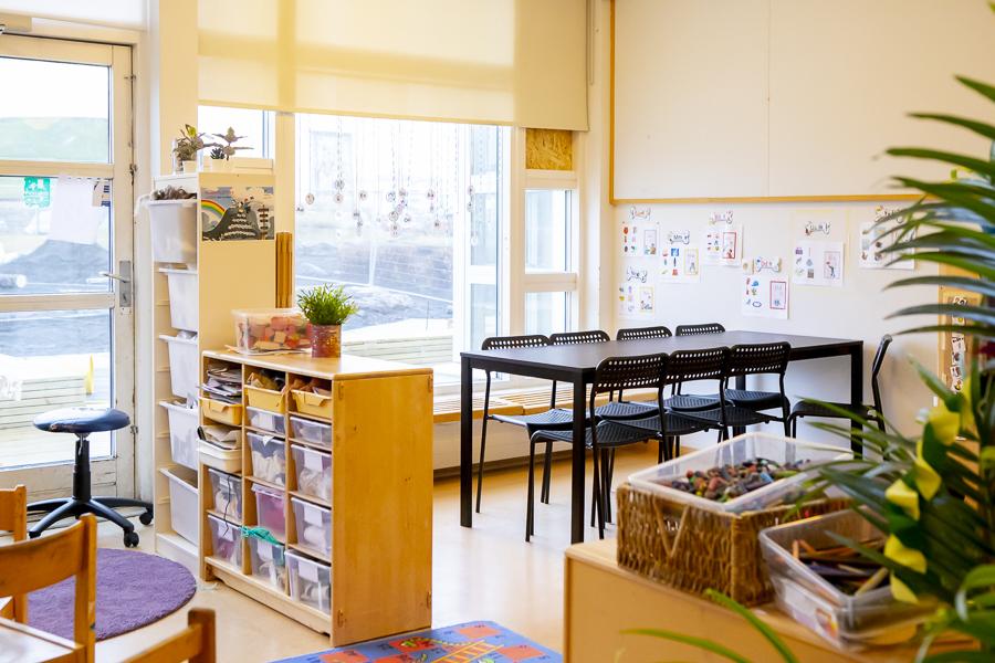 Looking into one of the rooms at Klambrar preschool. Black table and chairs, shelves with toys and other furniture.