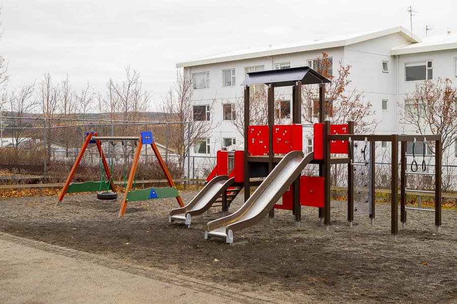 Leikkastali með rennibrautum og rólur á útileiksvæði leikskólans Sunnufoldar