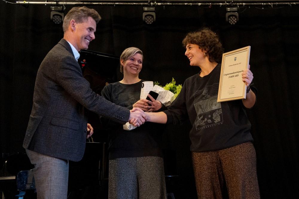Skúli Helgason afhendir forsvarskonum ungmennadanshópsins FORWARD viðurkenningu fyrir Listhóp Reykjavíkur árið 2023, á sviðinu í Iðnó.