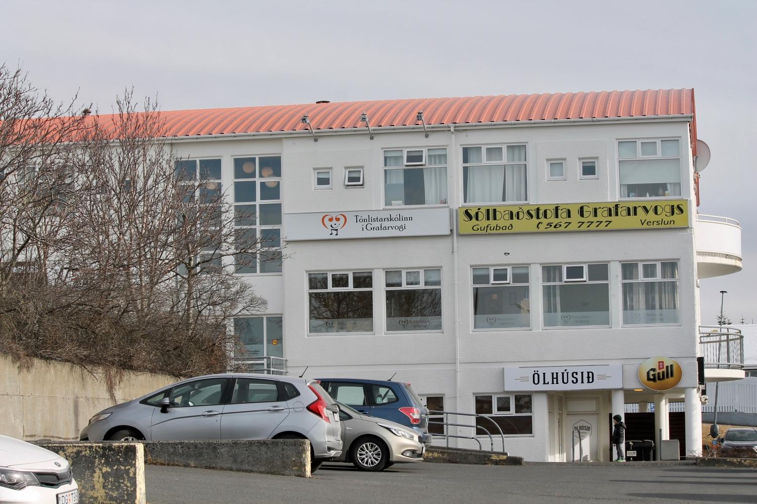 Hús Tónlistarskólans í Grafarvogi og bílar á bílastæði.