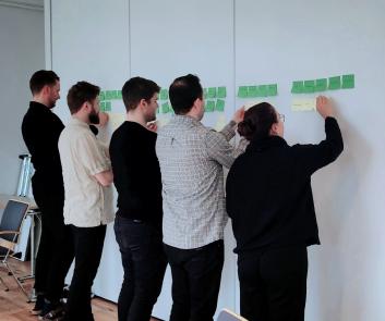 People sticking post-it notes with ideas on a wall.
