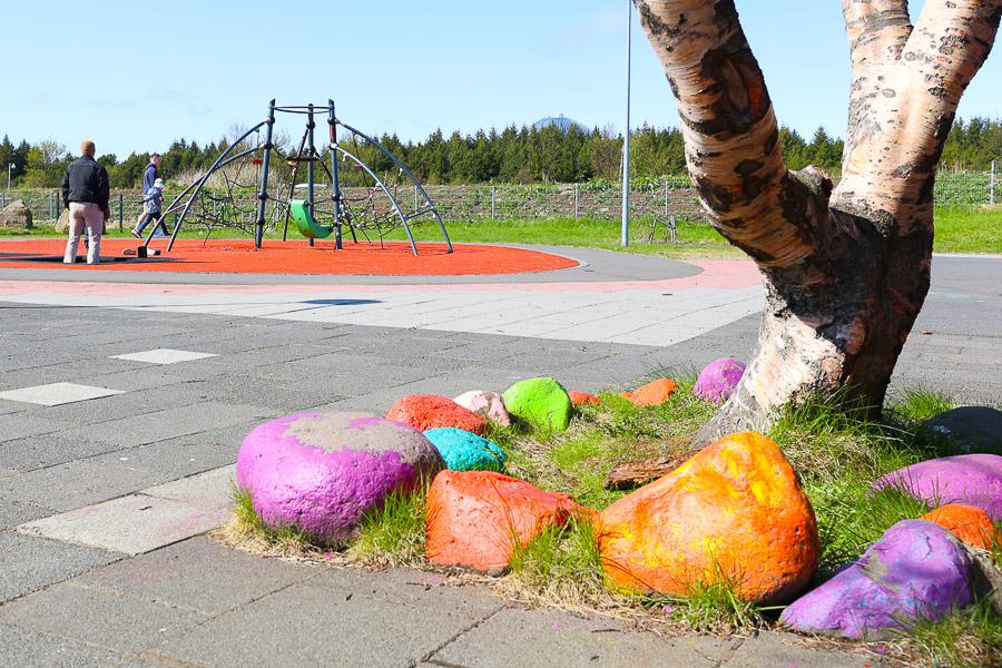 Tree stumps and large stones painted in various colors. Jungle gym in the background. 