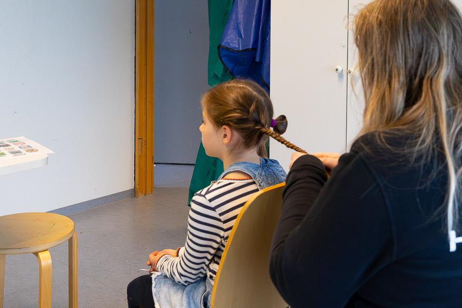 Barn að flétta hárið á öðru barni. 