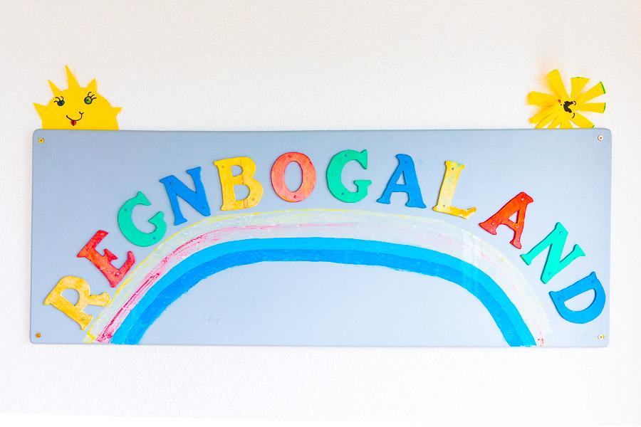 A sign that reads "Regnbogaland" with a picture of a rainbow. 