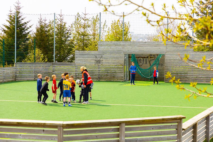 Children playing soccer on an outdoor grass field.