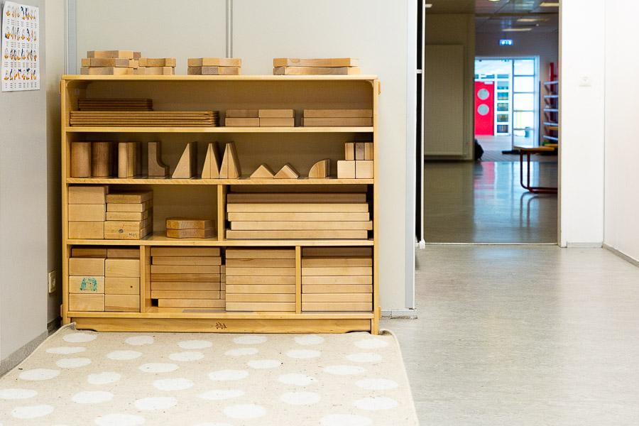 A shelf with large wooden blocks and a door to the next room. 