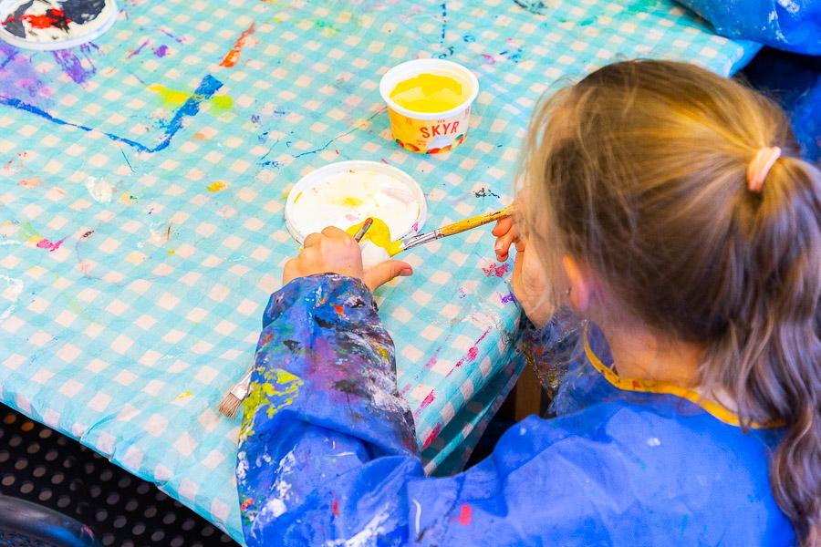 A child sits at a table painting. 