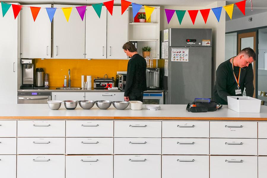White kitchen with bunting hanging from the ceiling. Young people and instructor engaged in activities. 