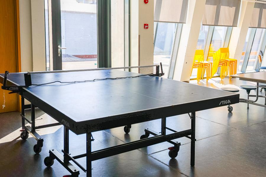 Hall with ping-pong table, tables and chairs. 