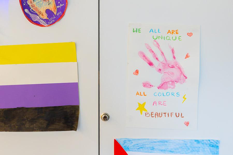 Flags on the wall along with a sheet displaying handprints. 