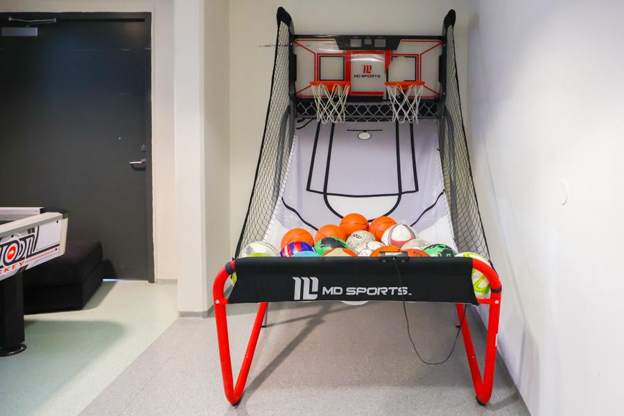 Small indoor basketball hoop with two baskets and multiple balls. 