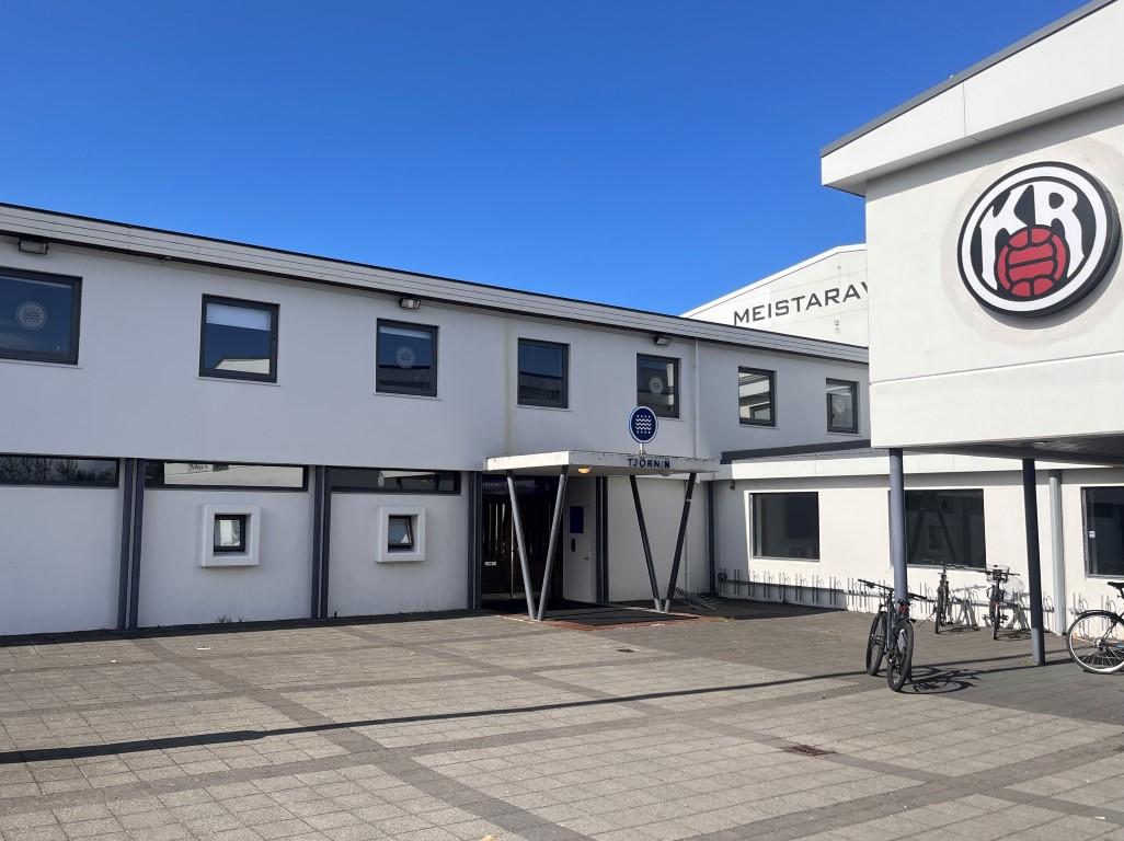 Photo of a white building with a sign that reads Tjörnin. Large KR logo on the right side of the building.