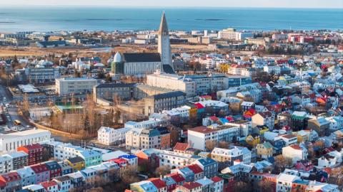 Aerial view of the city center, with Hallgrímskirkja church in the center, airport and ocean in the background. Sun.